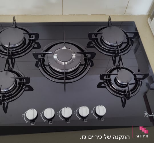 כיריים גז שחורות עם חמישה מבערים וכפתורי שליטה